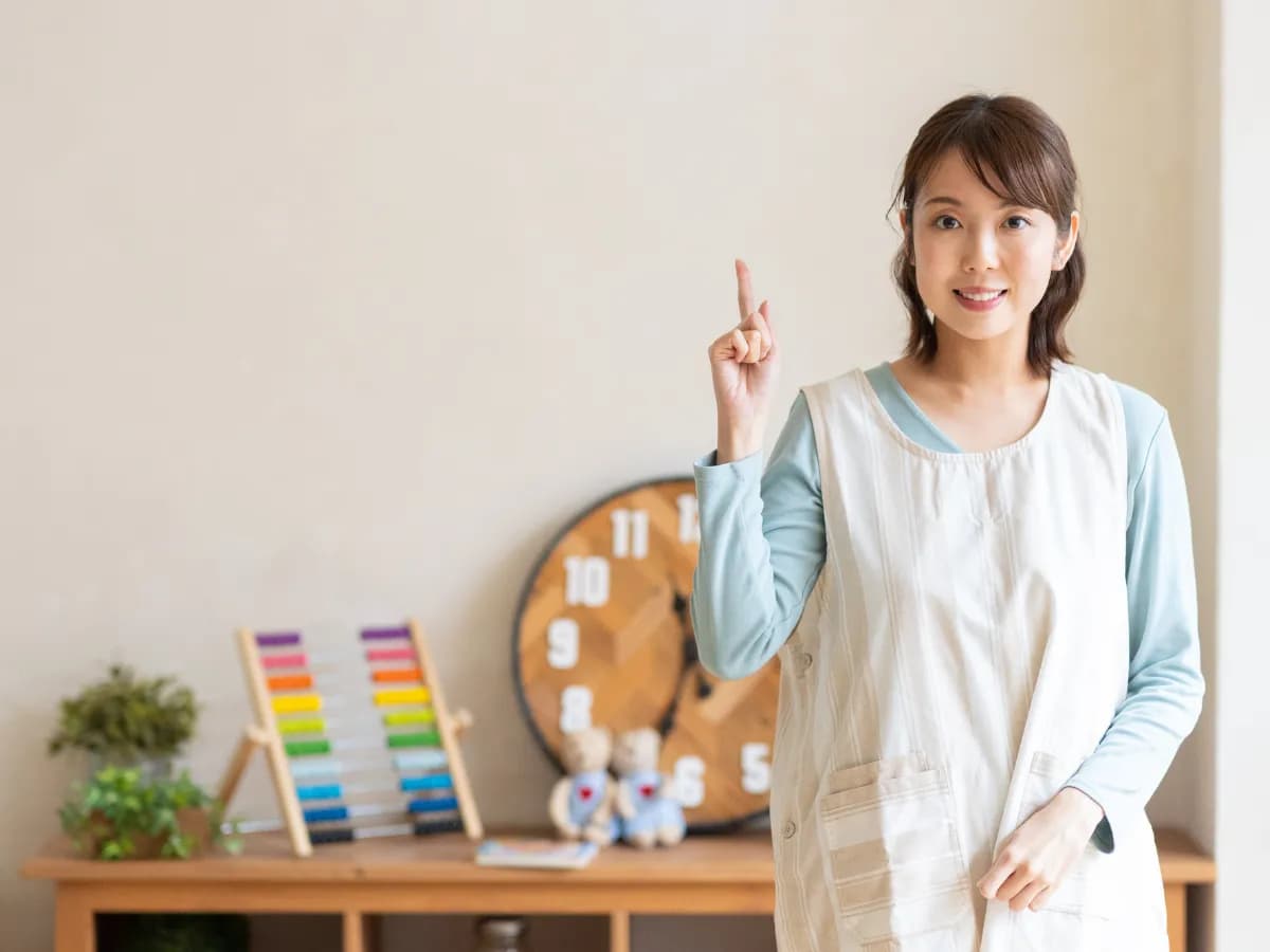 人差し指を上げている女性の保育士のイメージ