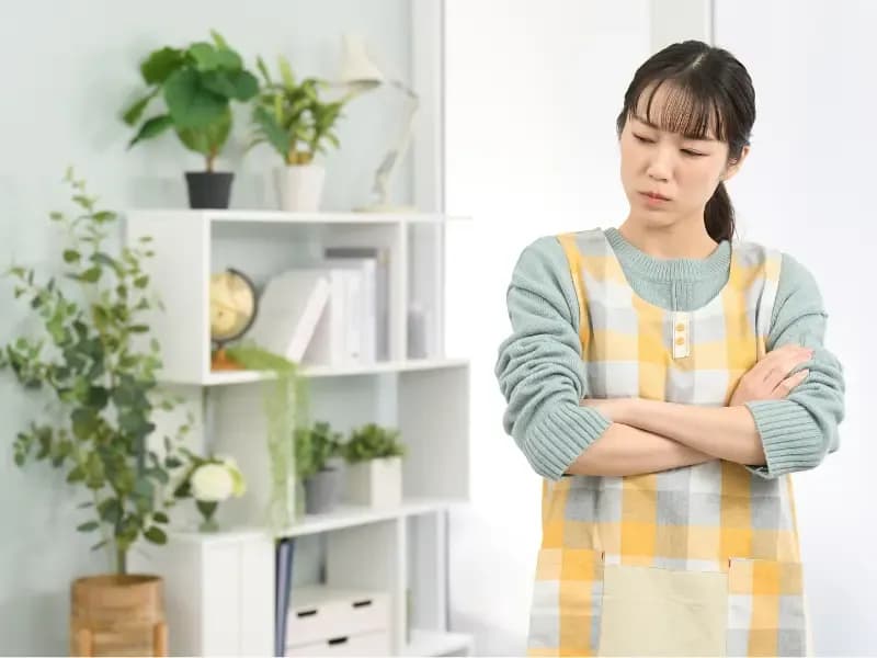悩むエプロンを着た女性の画像