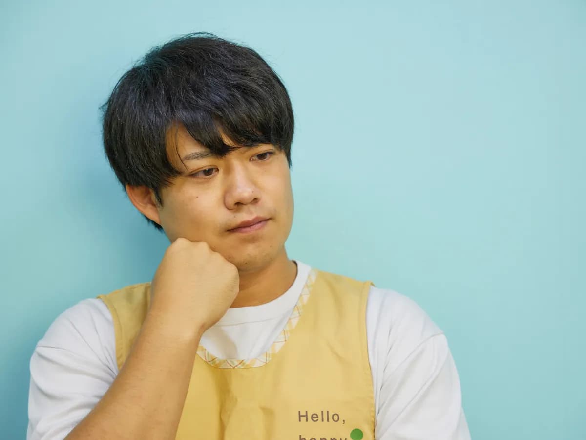 あごに手をあてて考え込む男性保育士のイメージ