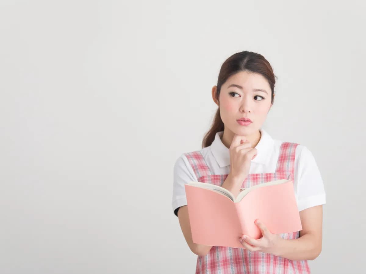 本をもって悩む保育士の画像