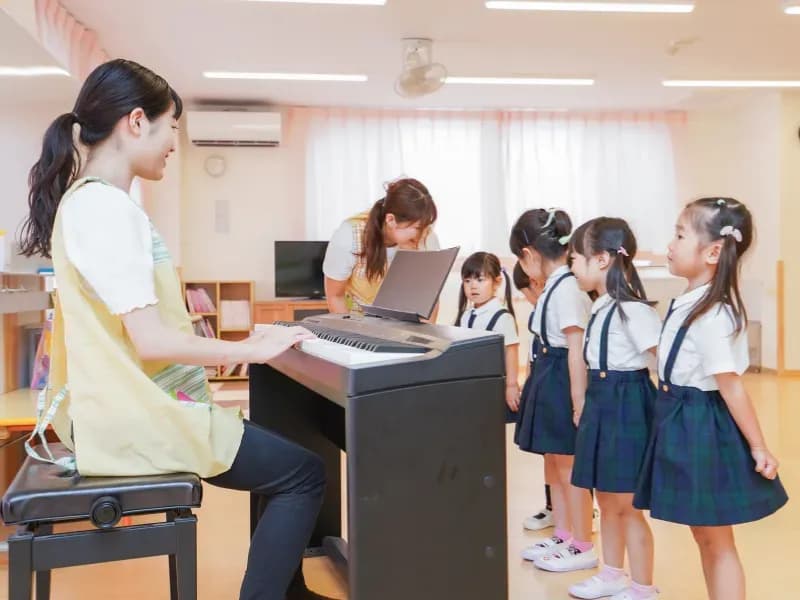 ピアノを弾く保育士と複数人の園児のイメージ
