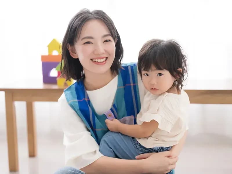 笑顔で子供を抱っこする保育士のイメージ