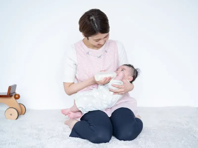 ミルクをあげる女性保育士のイメージ