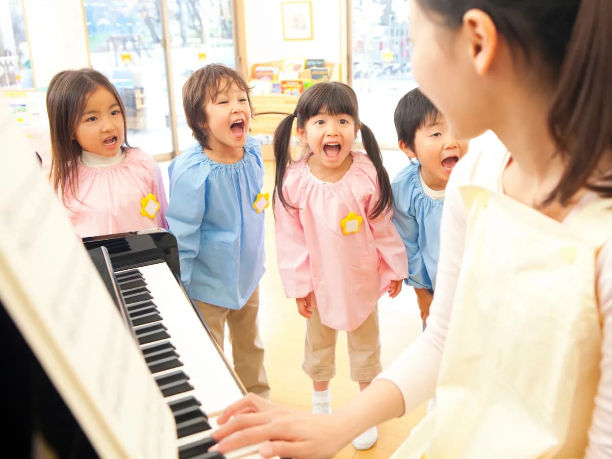 幼稚園教諭のピアノに合わせて歌う幼稚園児のイメージ