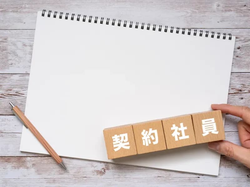 契約社員と書かれた木箱とペンとノートの画像