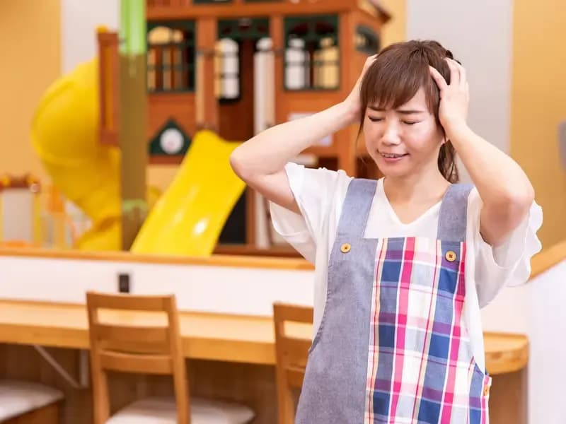 頭を抱え悩む主任保育士のイメージ