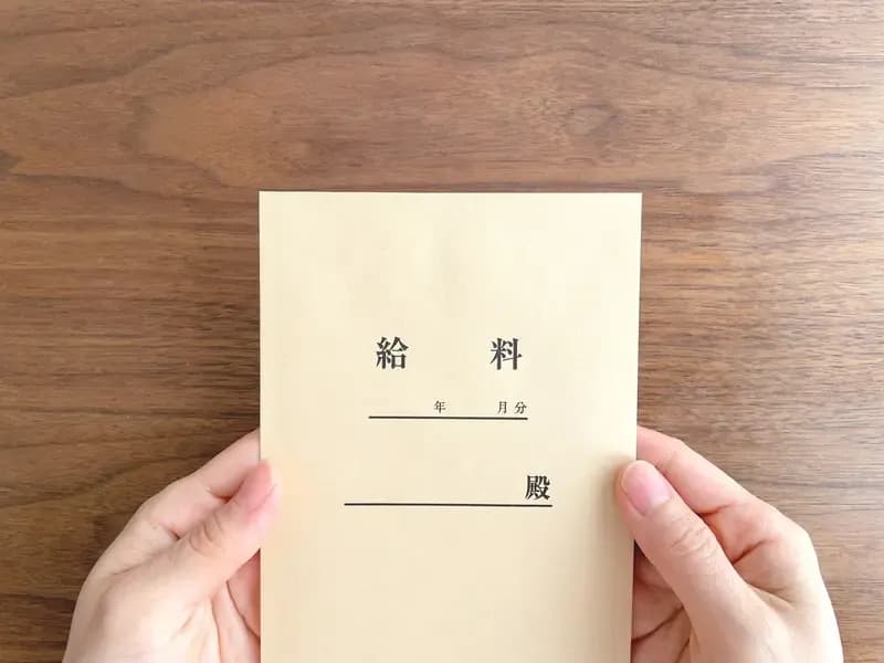 テーブルで給料袋を持つ女性の手元のイメージ