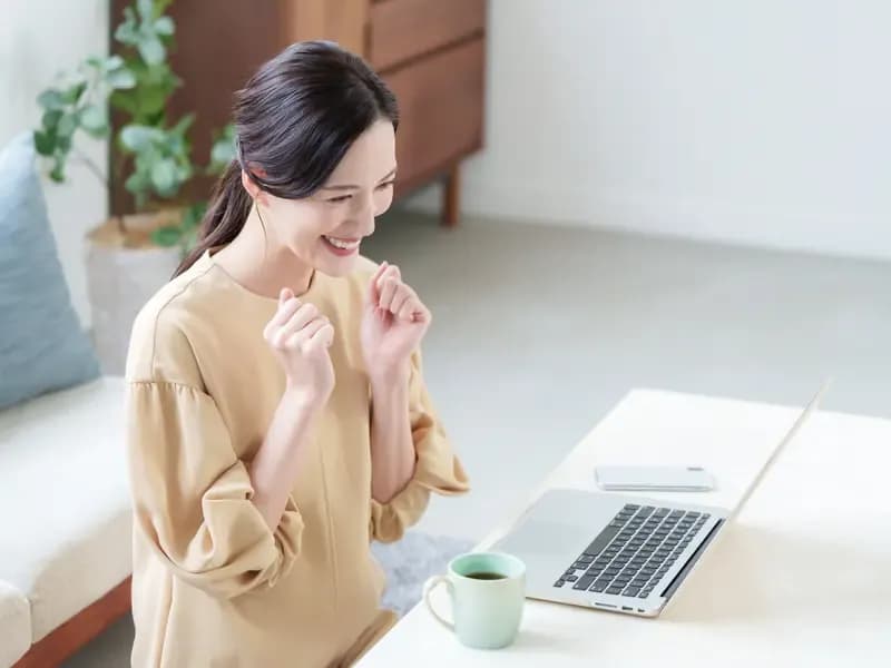 PCを見ながら喜ぶ女性のイメージ
