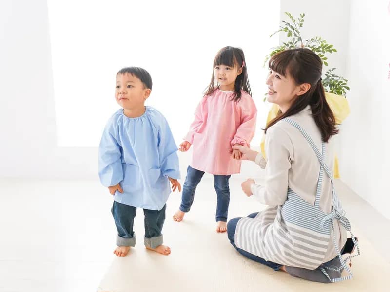 男女の幼児と保育する女性