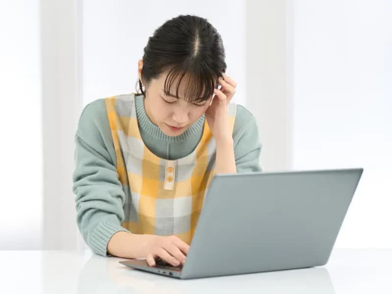 PCの前で頭を抱える保育士の画像