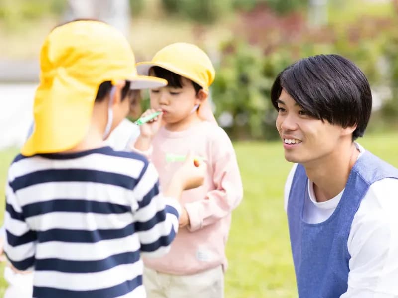 公園で遊ぶ保育士と園児の画像