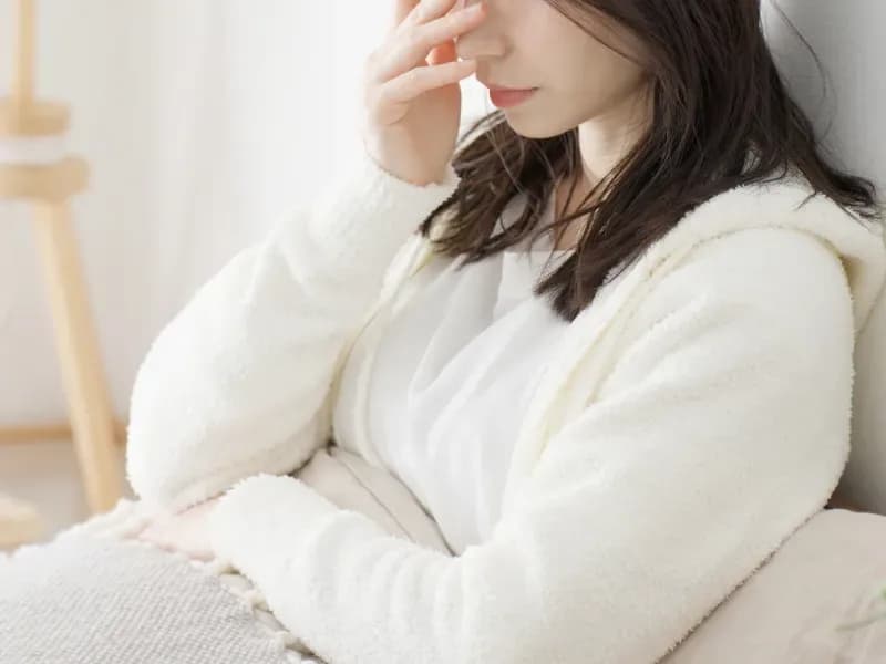 ベッドの上で頭を抱える女性の画像