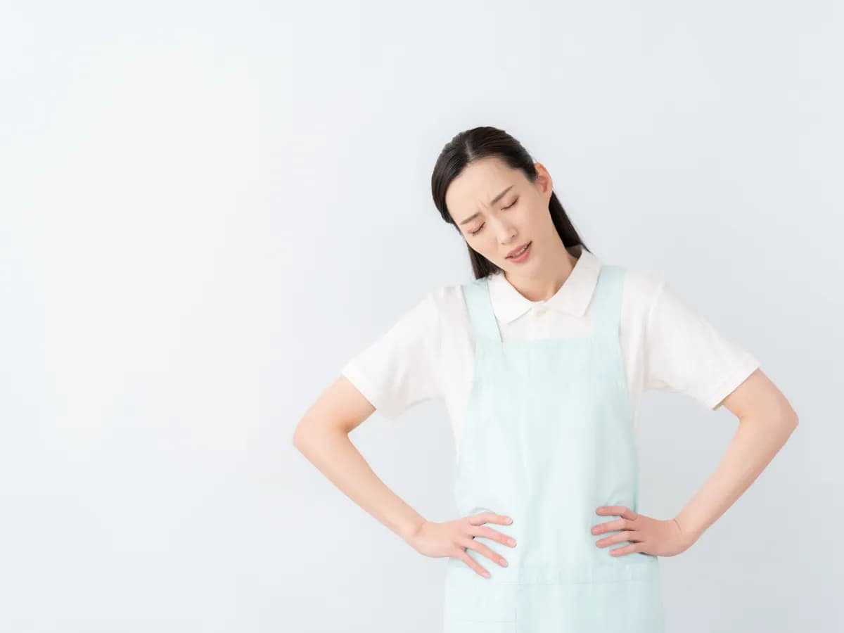 腰に手を当ててため息をつく保育士のイメージ