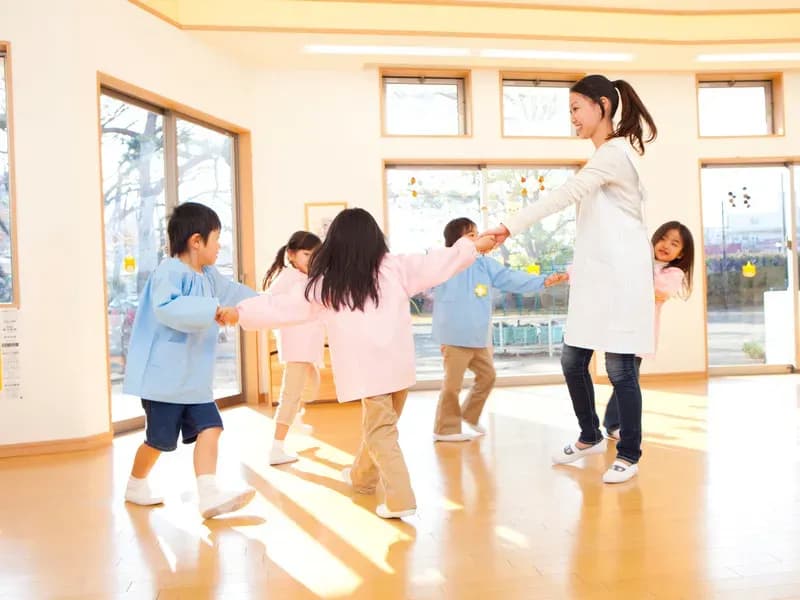 輪になって踊る幼稚園教諭と幼稚園児