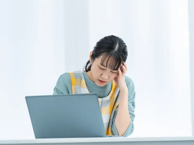 PCの前で思いつめる保育士の画像