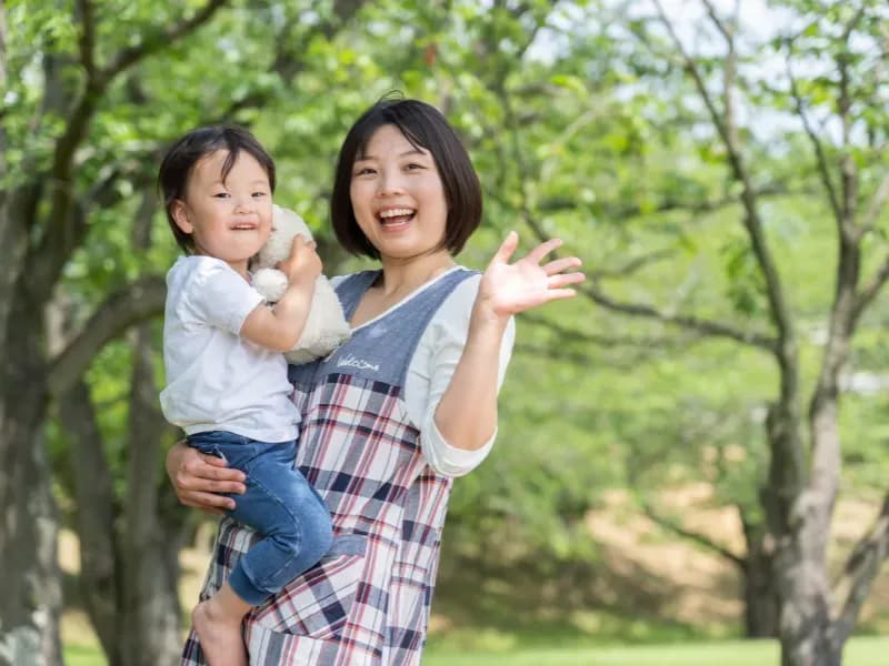 園児を抱っこしながら微笑む保育士の画像