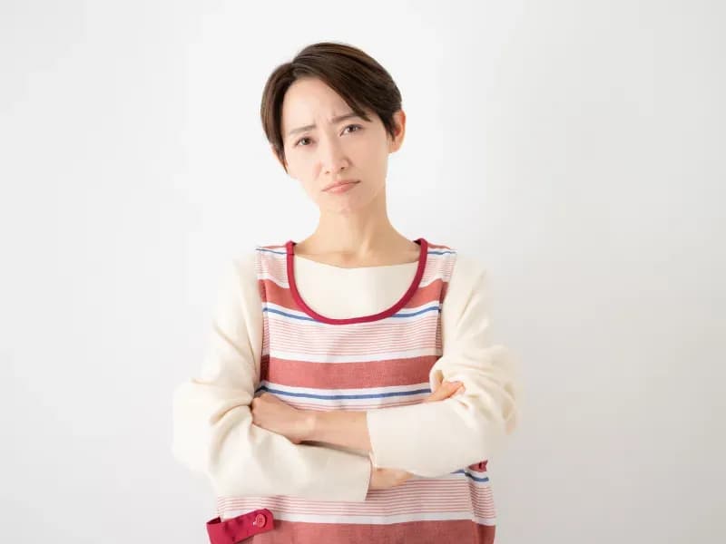 腕を組んで困った顔をする保育士の画像