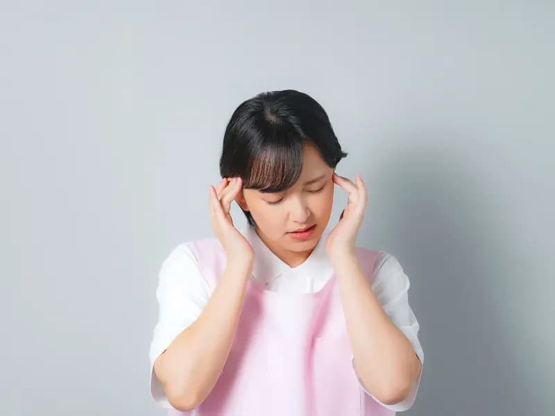 頭を押さえて悩んでいる保育士の画像