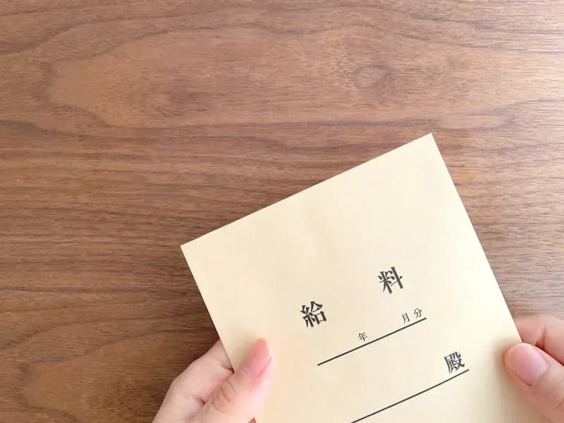 机の上で給料袋を持つ女性の手