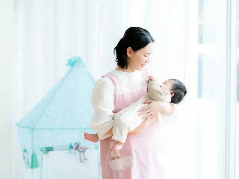 乳児を抱く保育士の画像
