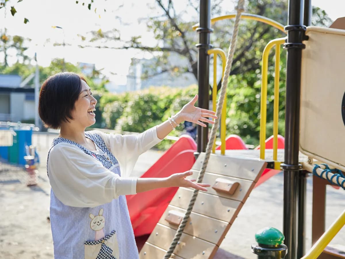 子どもと遊具で遊ぶベテラン保育士の画像