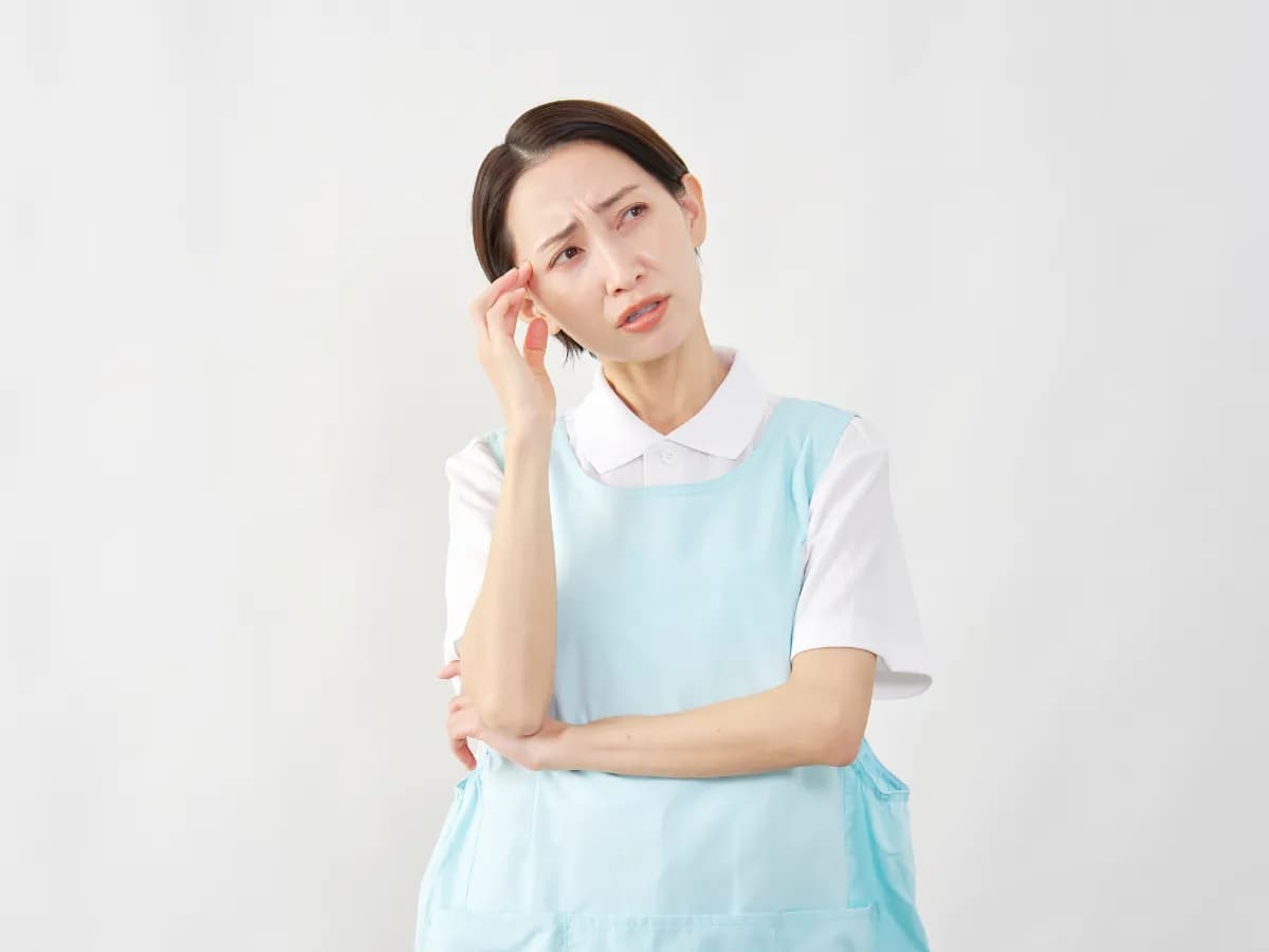 手を頭にあてて悩む保育士の女性の画像
