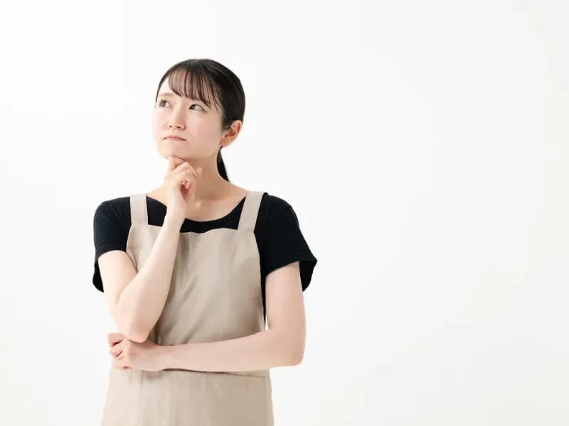 顎に手を当てて上を見て悩む保育士の画像