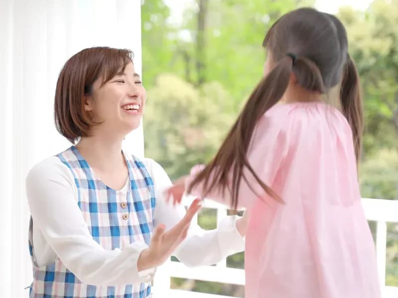 園児を笑顔で迎える保育士の画像