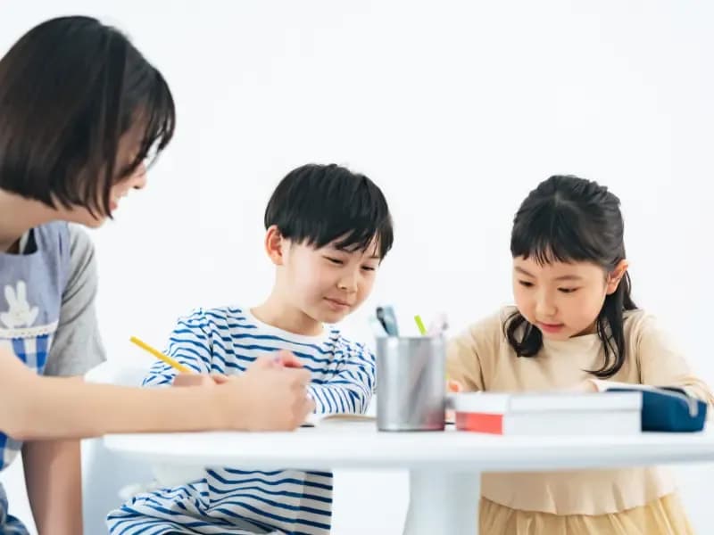 学童保育で勉強を教わる子供たちのイメージ