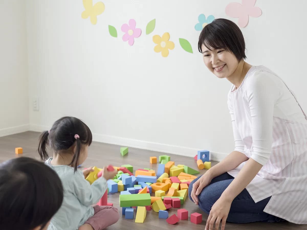 子供と積み木で遊ぶ保育士の画像