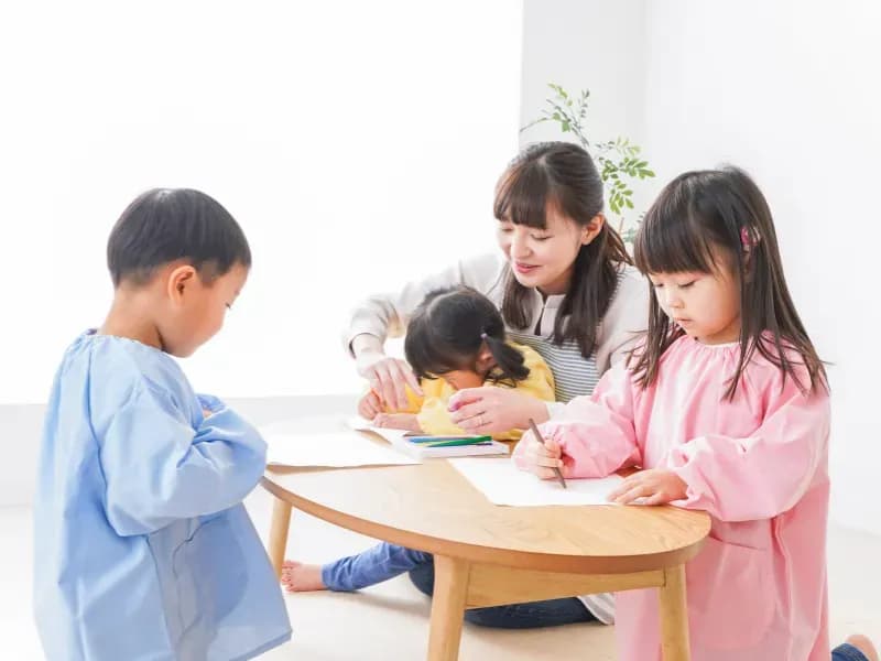 絵を描く保育士と子どもたちのイメージ
