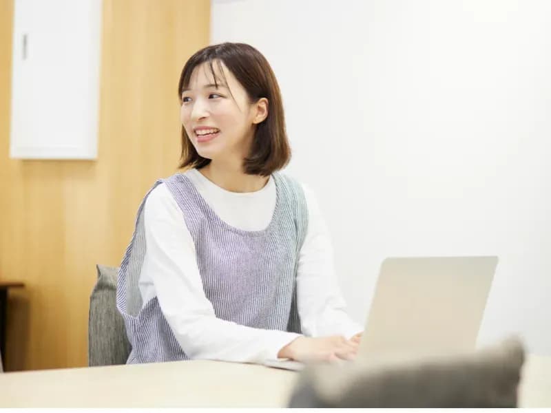 保育園でノートパソコンを使用して仕事をする保育士の画像