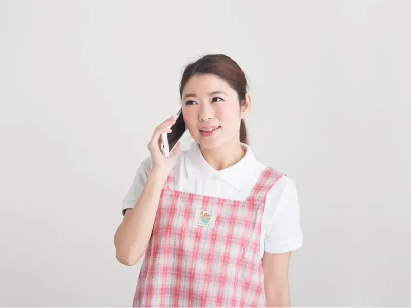 電話をする保育士の画像