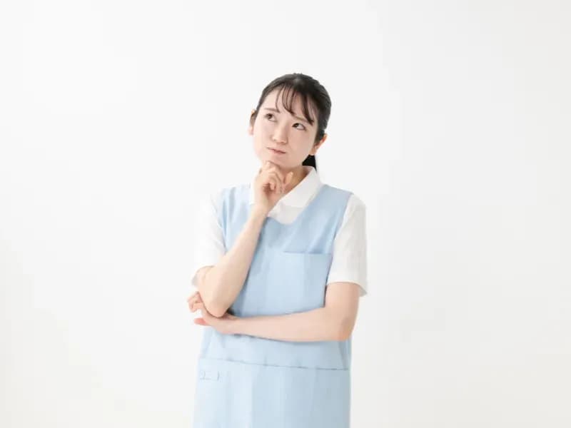 上を見ながら顎に手を当てて悩む保育士の画像