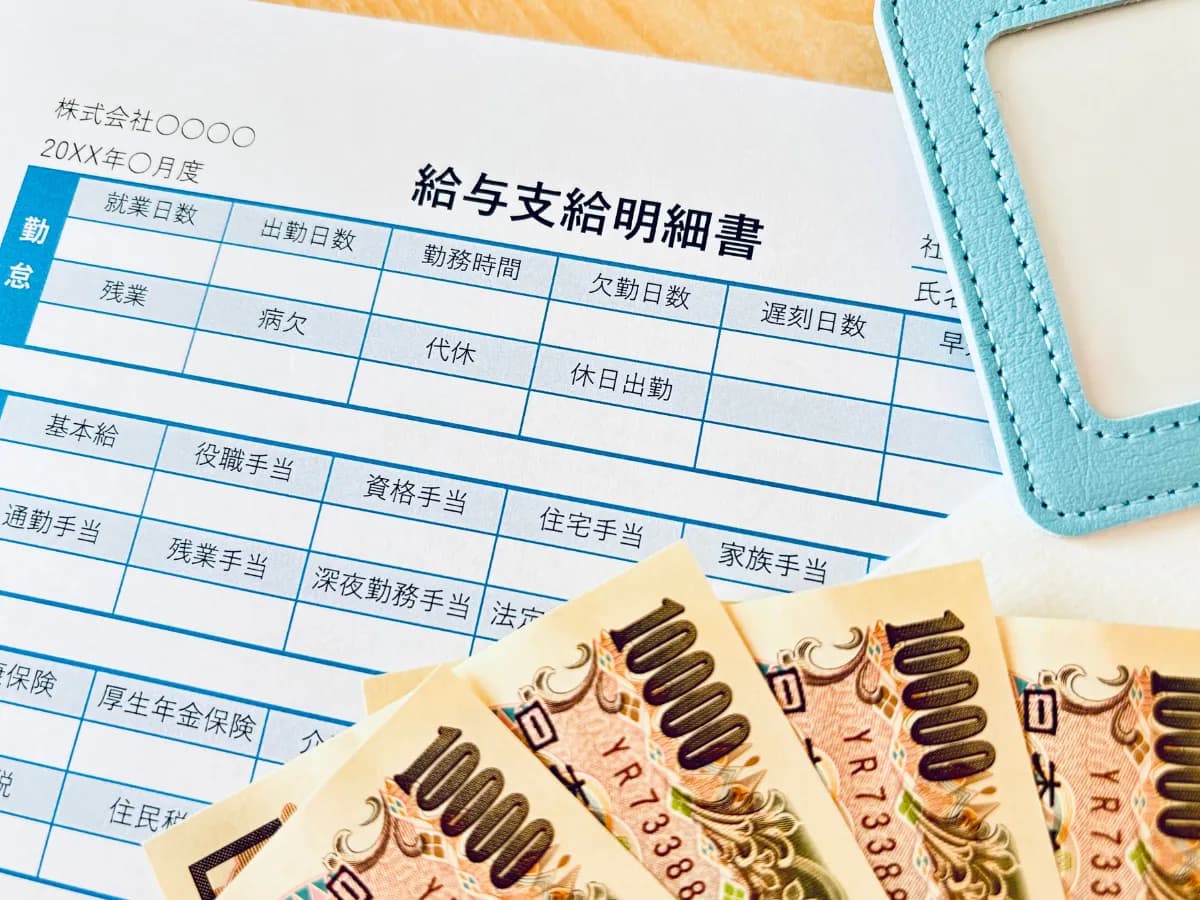 給料明細書と1万円札が置かれた画像