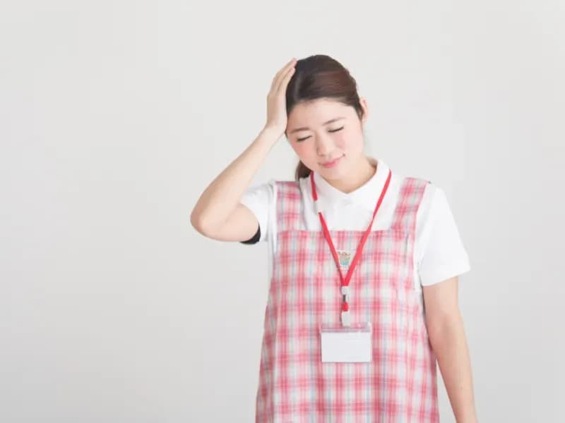頭に手を当てて困る保育士の画像