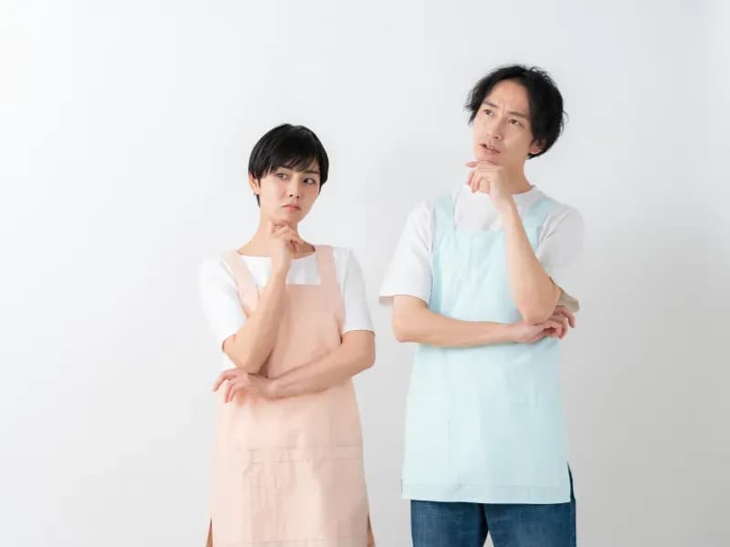 首をかしげる男女の保育士の画像