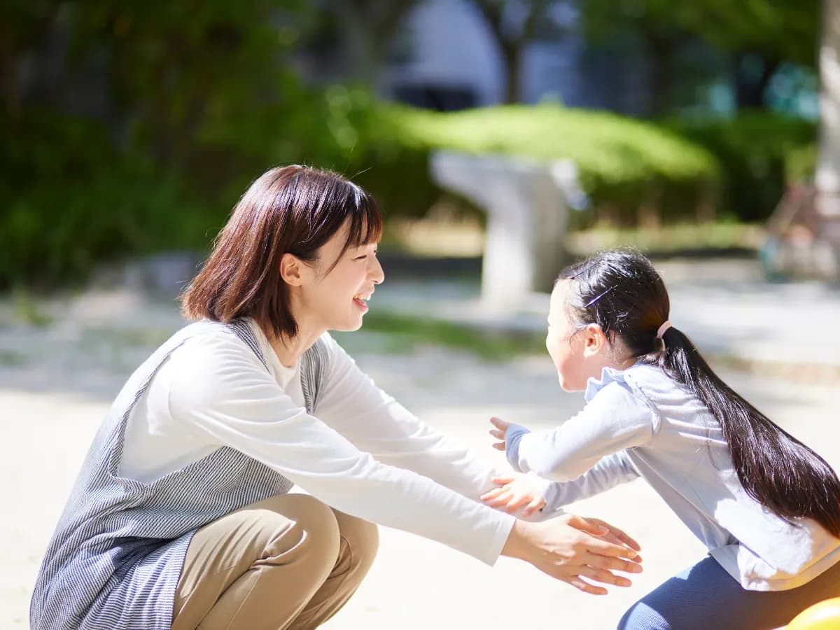 笑顔で子供と遊ぶ女性保育士の画像