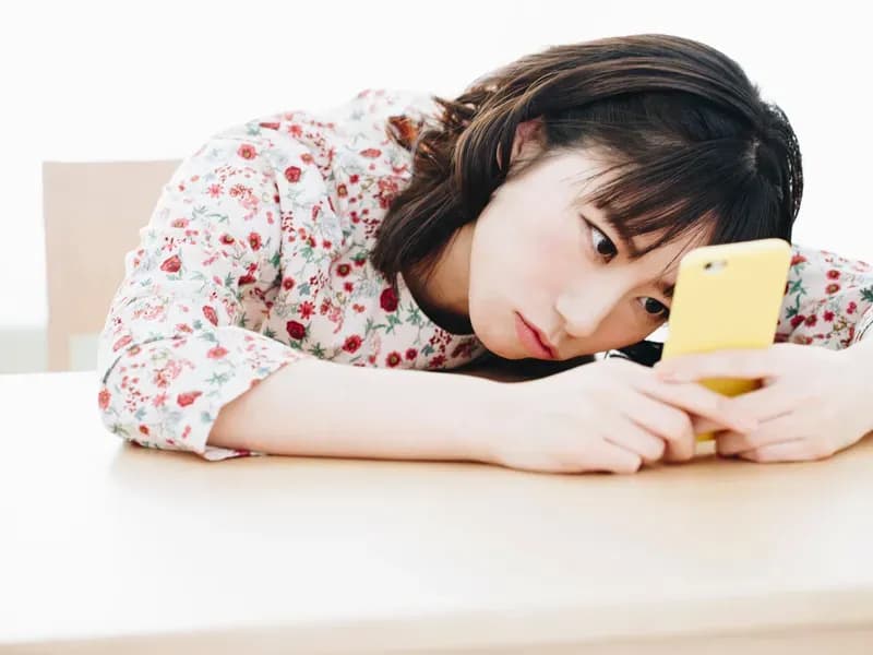 スマホ画面を眺めてうつ伏せになっている女性