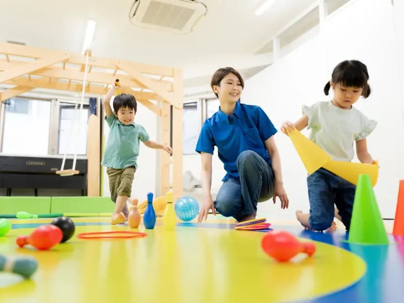 保育所で子供と遊ぶ大人のイメージ