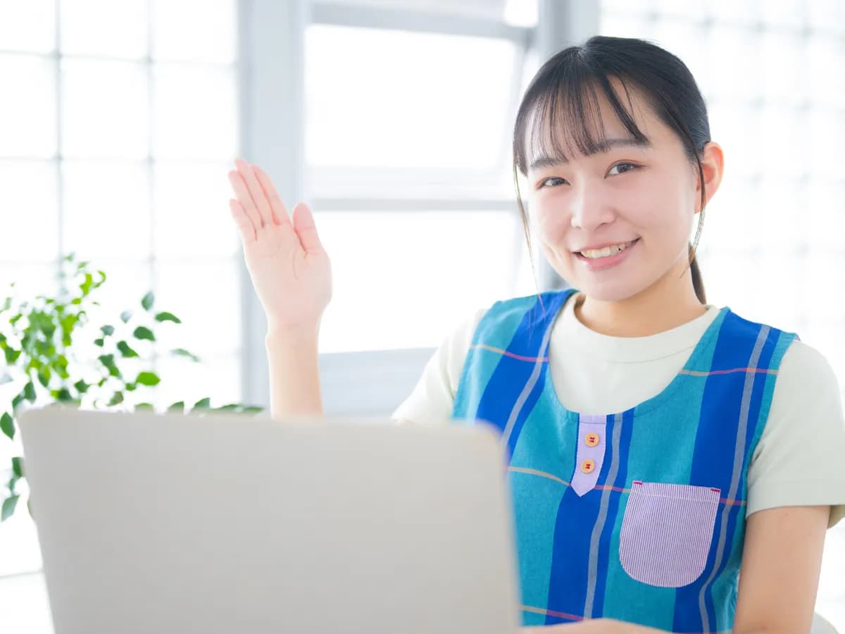 パソコン作業をする女性保育士の画像