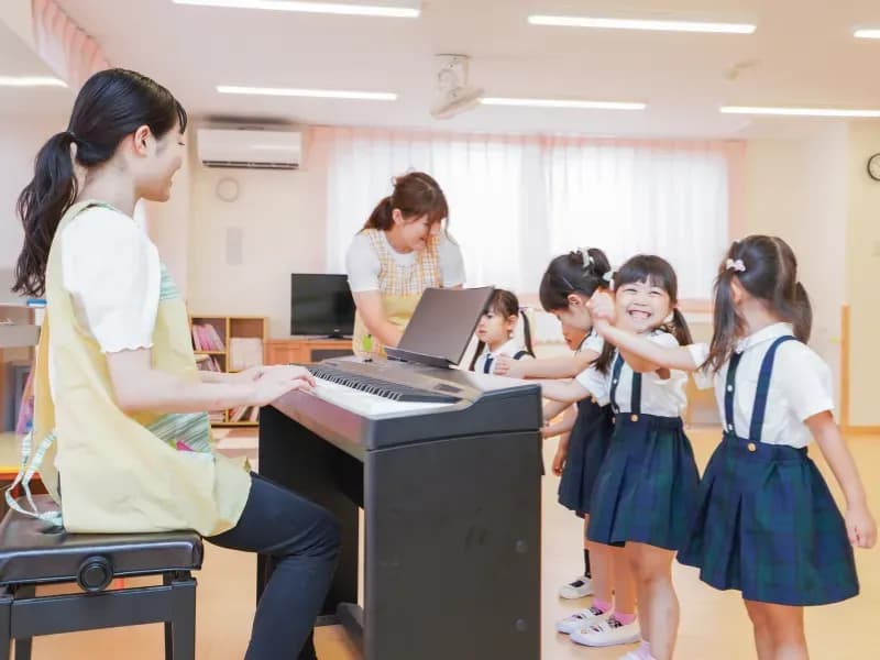 ピアノを弾く保育士と園児の画像