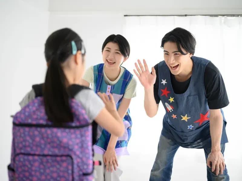 学童などでバイバイする子どもと保育士の画像