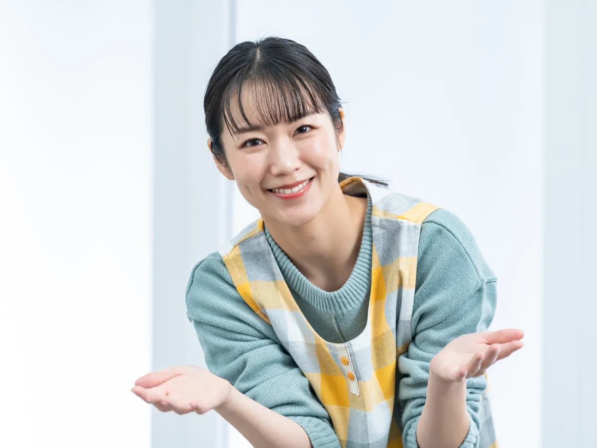 笑顔で手を広げるエプロン姿の女性の画像