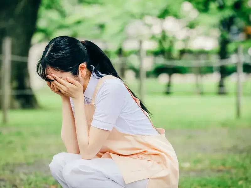 顔を覆って落ち込み悩む保育士のイメージ