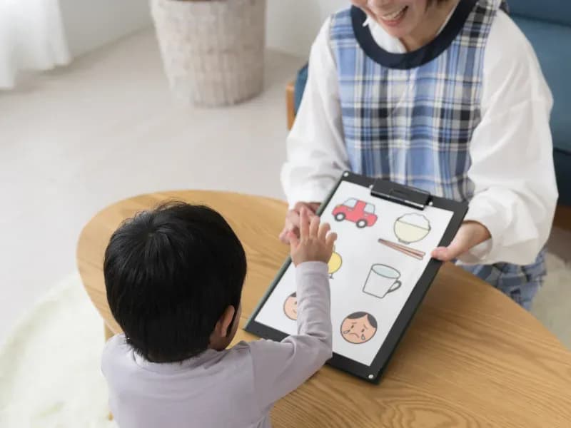 子供に絵を見せている保育士のイメージ