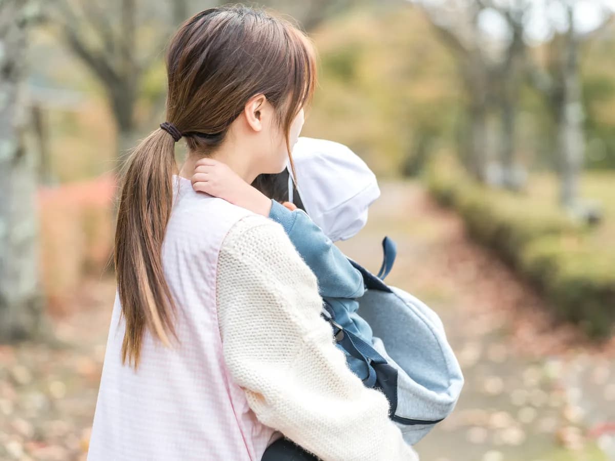 園児を抱っこする保育士の後ろ姿のイメージ
