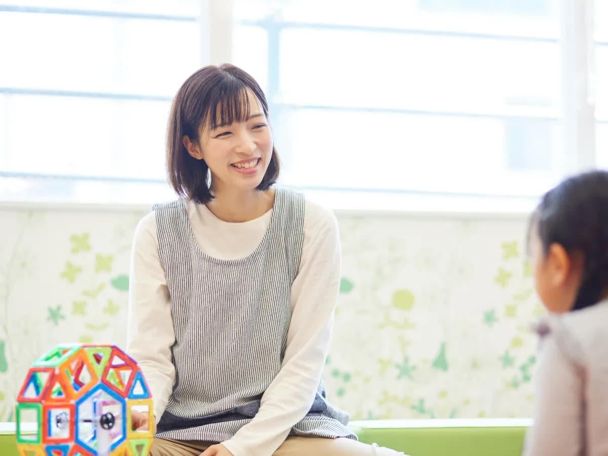 託児所でおもちゃで子供と遊ぶ保育士の女性