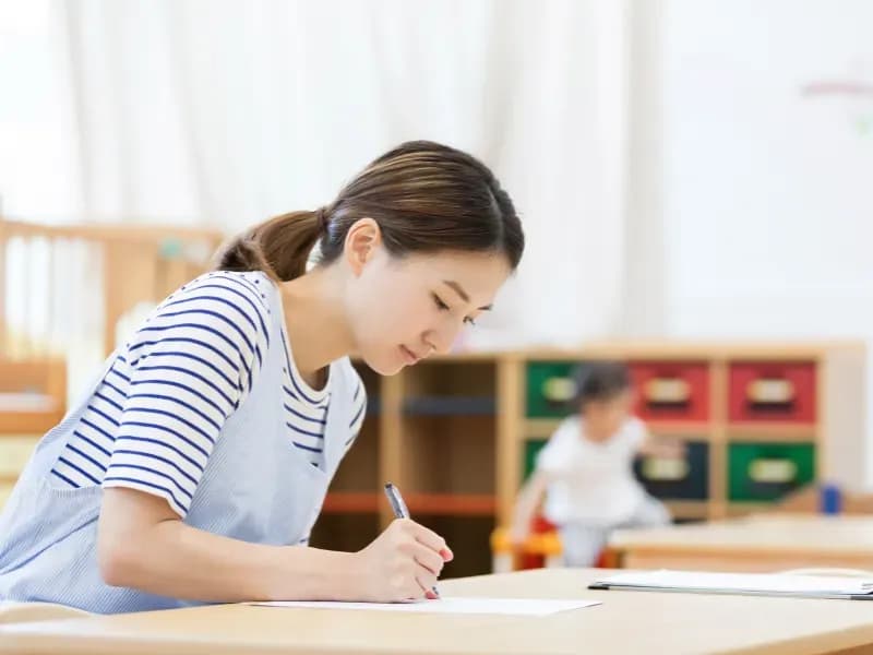 書類を書く保育士の画像