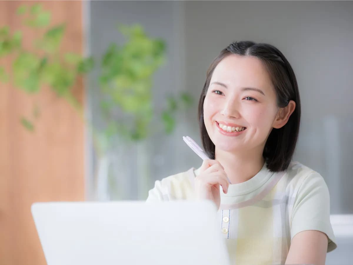 ノートパソコンを開いているエプロン姿の笑顔の女性のイメージ